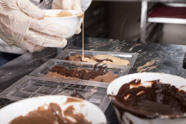 Plastik kalıplar içine eritilmiş sütlü çikolata dökme.