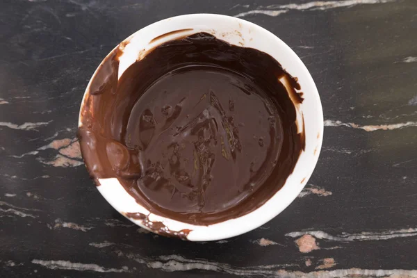 Растаявший горячий шоколад в белой пластиковой миске . — стоковое фото