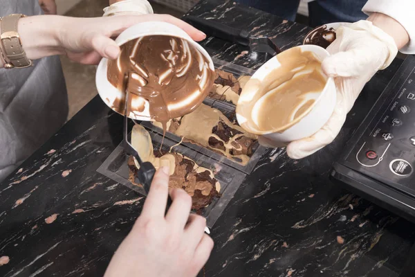 Наливание расплавленного шоколада в пластиковые формы . — стоковое фото