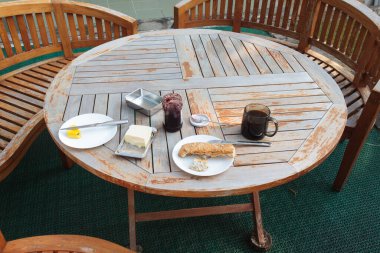 Sıcak terasta güzel bir kahvaltı. Bunların hepsi ahşap bir masanın üzerinde. Yakın plan..