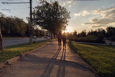 Gün batımında sokakta iki kişinin silueti. Şehrin güzel günbatımı.