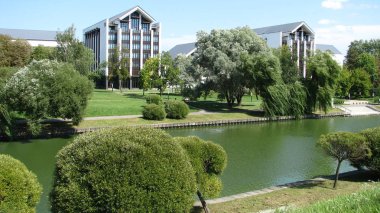 Güzel süs çalılar ve su kanalının kıyısında ağlayan söğütler. Şık mimari yapılar. Minsk.