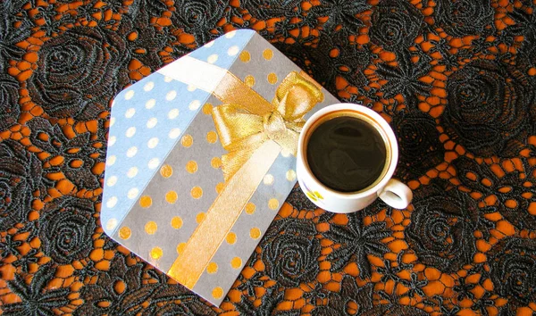 Bir fincan kahve ve dantel siyah masa örtüsü üzerinde bir tebrik zarfı.