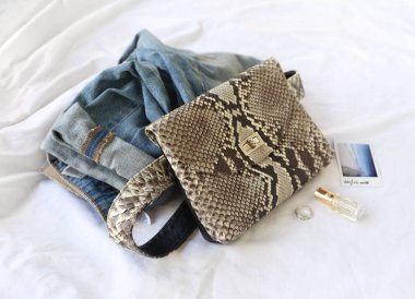 Moda kadın aksesuarları. Temel genel bakış. Python deri kemer çanta, denim ve kozmetik üstten görünüm 