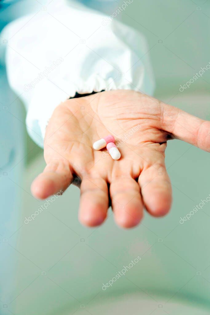 Doctor holding white and pink pills in his hand