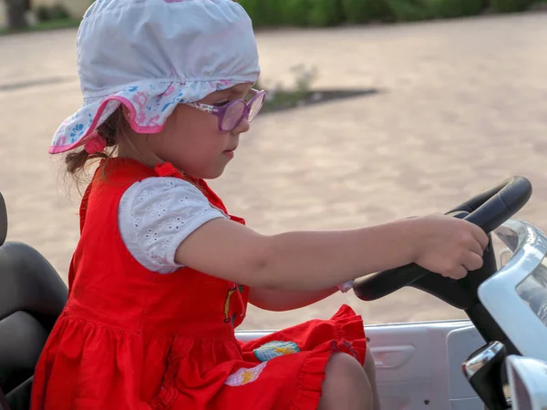 Una Chica Años Sombrero Gafas Monta Coche Eléctrico Juguete Blanco — Foto de Stock