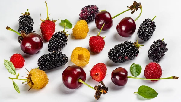 Fruit collection on a white background with mulberry, red raspberries, raspberries, blackberries, cherries, mint leaves