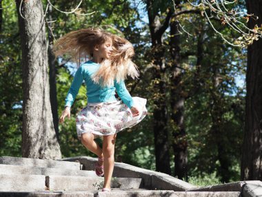 atlayış sırasında gelişen uzun sarı saçları ile parkta tatilde mutlu ve neşeli kız 9 yıl