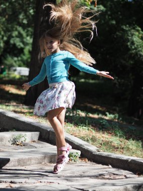atlayış sırasında gelişen uzun sarı saçları ile parkta tatilde mutlu ve neşeli kız 9 yıl