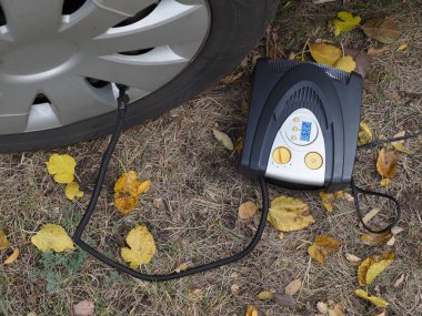 Sönük araba tekerleğini hava kompresörüyle ayarlanmış basınca pompalıyorum.