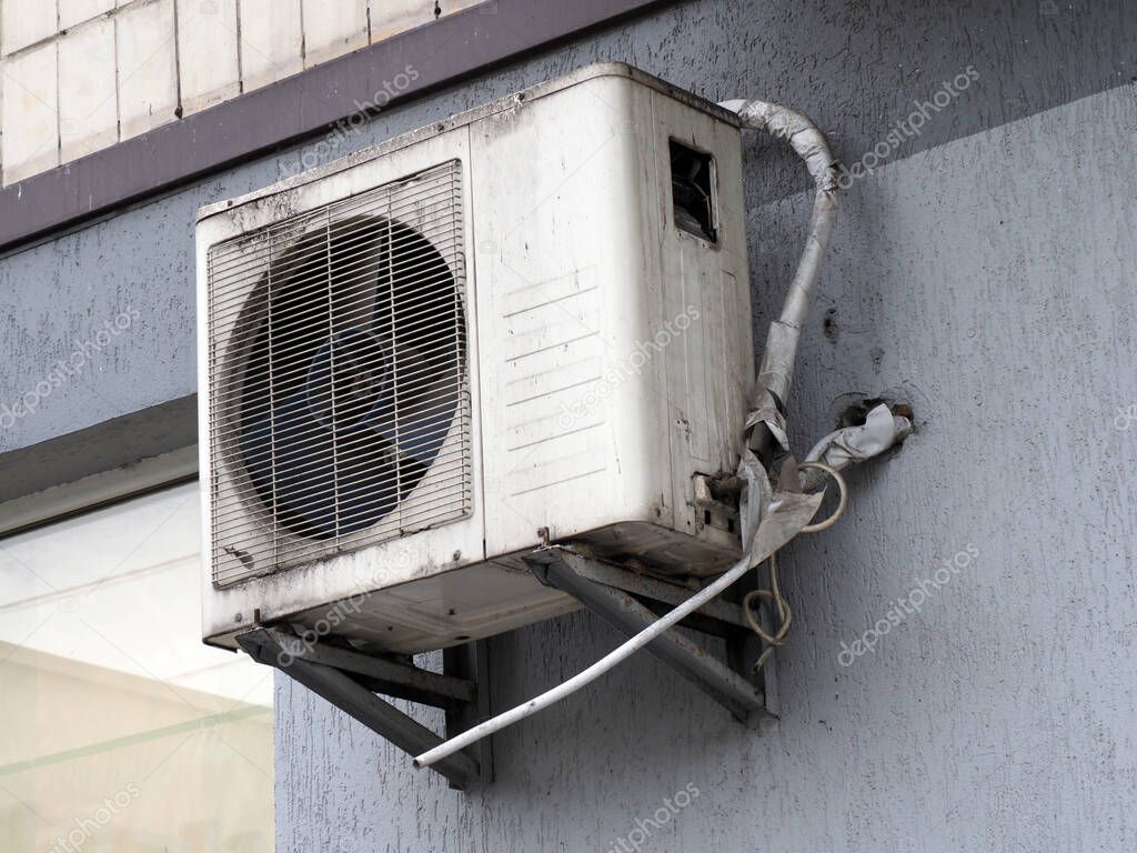 old outdoor air conditioning unit on the facade of the house