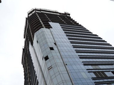 Gri gökyüzünün arka planında bir gökdelenin parıltısı