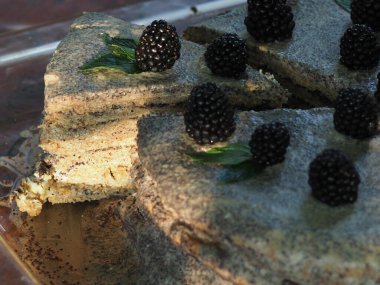 Ev yapımı haşhaş tohumu ile doldurulmuş un ve böğürtlenlerle süslenmiş kek.