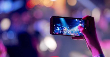 Akıllı telefonlu canlı müzik konserinin görüntülerini kaydeden eller..