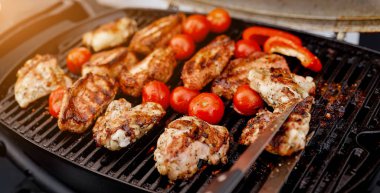 juicy roasted meat, tomatoes, red pepper on the grill on the street clipart