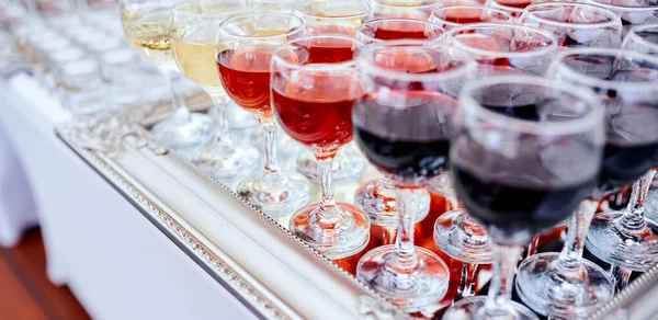 Многие бокалы из виноградной лозы наполнены красной и белой лозой и стаканами, заполненными на зеркальной скатерти. кейтеринг — стоковое фото