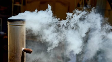 Tahta bir evin arka planında beyaz duman olan semaverden gelen boru..