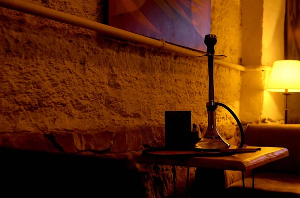 Cuarto oscuro con lámpara de pie de trabajo, y hookah negro en la mesa . —  Fotos de Stock
