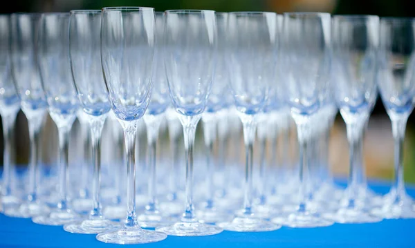 Una copa llena de copas de vino sobre mesa azul —  Fotos de Stock