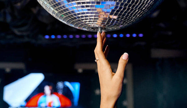  Beautiful female hand reaches for the disco ball and swings it