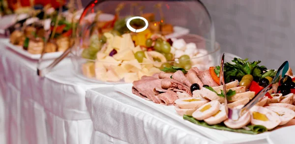 Catering. Uma mesa com toalha de mesa branca. Prato de carne, legumes, queijo e uvas — Fotografia de Stock