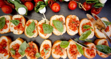 Sandviçler küçük kruterlerin üzerinde parıldıyor siyah tepside ve domateslerde.