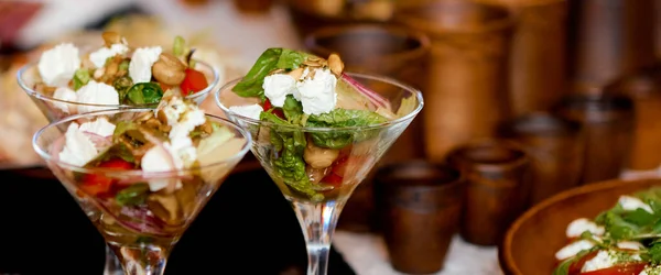 Três porções de salada em copos de martini na mesa. Utensílios de argila no fundo . — Fotografia de Stock
