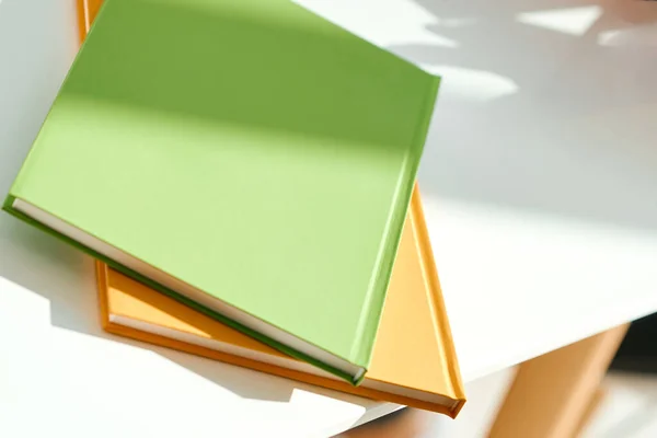 Δύο σημειωματάρια, πράσινα και πορτοκαλί, βρίσκονται στην άκρη της λευκής επιφάνειας εργασίας — Φωτογραφία Αρχείου