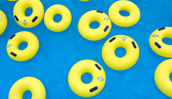 Several yellow swimming inflatable rescue laps on the blue water in the pool — Stock Photo, Image