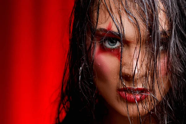 Angry young woman with a mecap in the form of a star on the eye on a red background