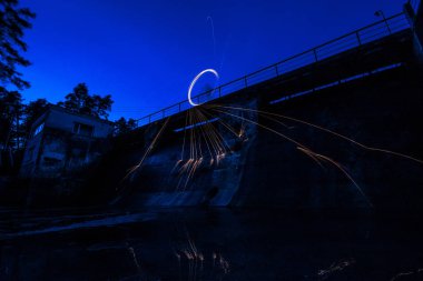 Yanan çelik yün eski baraj yakın spinned. İplik çelik yün parlayan kıvılcımlar duş. Uzun pozlama. Suda inanılmaz yansımalar. 