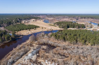 Sahil sahilinde havadan görünüm uçuşu, eriyen buz. Kumlu kıyı, göl, orman ve kar üzerinde havadan görünüm. 