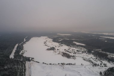Karla kaplı gölün havadan görünümü. Orman.
