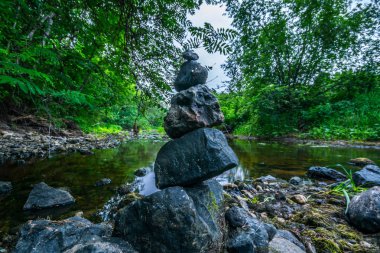Bir deredeki taşlar (taş piramidi). Su uzun pozlama ile bulanık. Yaz akşamı.