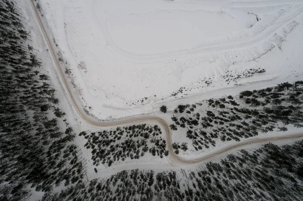 Aerial view of lake covered with snow. Forest.