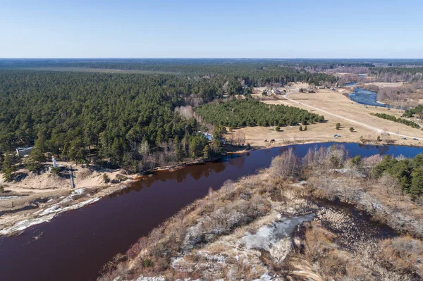 Aerial View Flight over the beach coast, melting ice. Aerial view over sandy coast, lake, forest and snow.