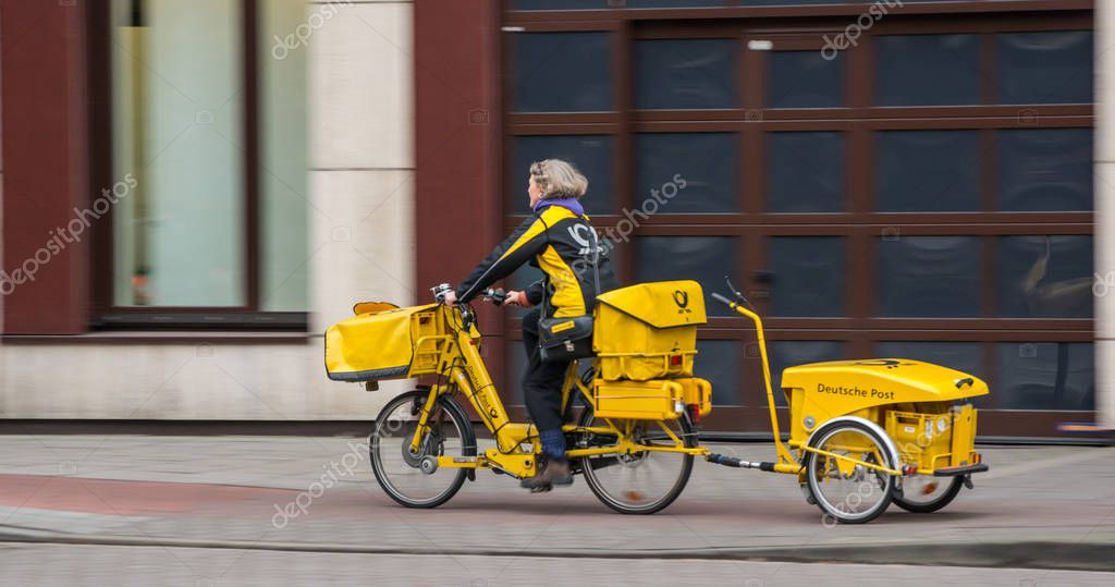 Hamburg, Germany - December 25, 2017: Typical German Postwoman with their yellow Bicycle distributes mail six days a week in Hamburg, Germany.