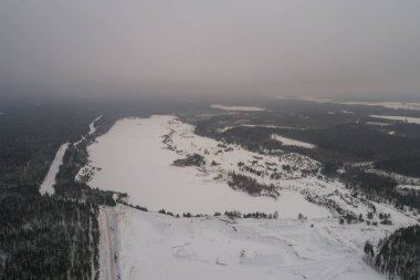 Karla kaplı gölün havadan görünümü. Orman.
