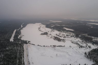 Karla kaplı gölün havadan görünümü. Orman.