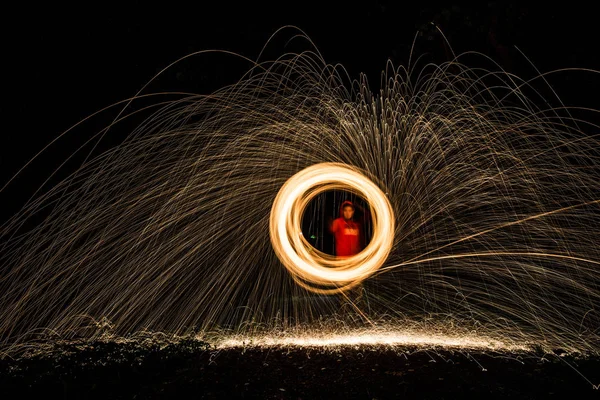 Aerial view of man spinning burning steel wool. Showers of glowing sparks from spinning steel wool. Drone view.