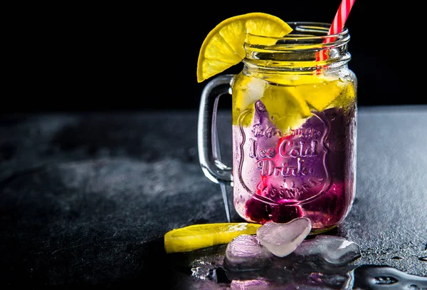Bir kalem ve saman ile cam kupa limon dilimleri ve buz ile Kokteyl. İngiliz soğuk içecekler klasik bir yazıt ile beyaz bir raf üzerinde duruyor