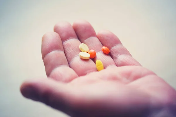 Yetişkin bir adamın eli haplarla dolu.