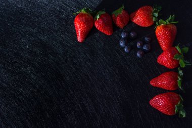 Çilekli çerçeve, yaban mersini ve kırmızı meyve ile dokular ile siyah tablo