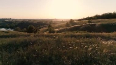 Gün batımı sıcak ışık ile aydınlatılmış yeşil tepeler ile geniş bozkır.