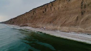 Genç ve sevgi dolu insanların bir çift, yaşam zevk, Öpüşme ve birbirlerini okşayarak, deniz kıyısında boyunca zaruks tutarak yürüyüş, ünlü kayalar ve deniz dalgaları arasında, quadrocopter video çekim
