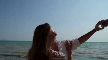 Deniz kıyısındaki temiz güneşli plajda rahatlatıcı iken Genç, sevgi dolu çift telefonda selfie yapar.