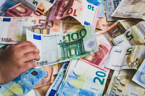 Bambino che ruba cento banconote in euro su più banconote in euro — Foto Stock