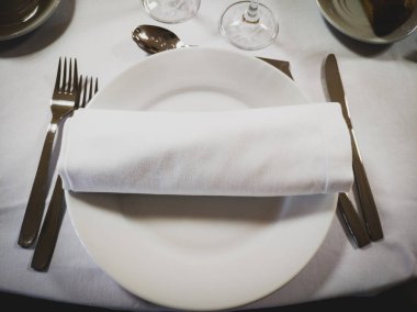 Yanlarında çatal bıçak takımı ile boş yuvarlak beyaz bir plaka üzerinde Peçete