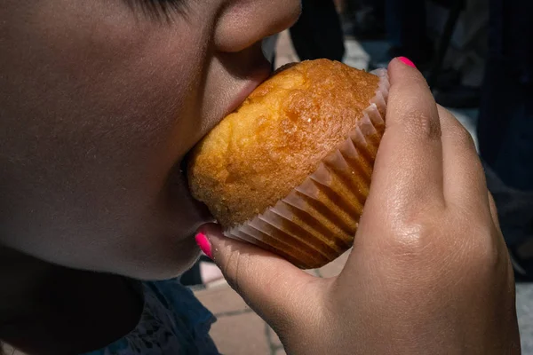 Девушка ест кексы с покрашенными ногтями — стоковое фото
