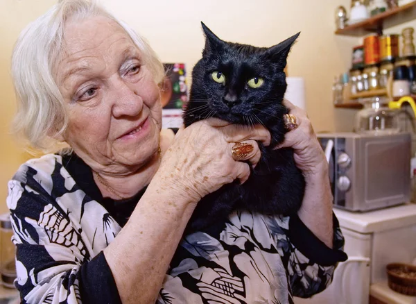 An old woman hugs her cat.